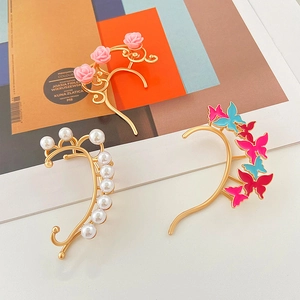 Elegantes earcuffs dorados con mariposas de colores, rosas rosas y perlas de imitación