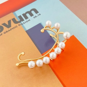 Primer plano detallado de un pendiente tipo earcuff dorado con perlas blancas elegantes
