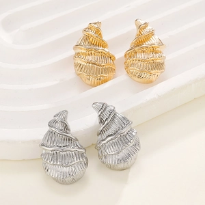 Elegant gold and silver conch-shaped spiral textured stud earrings on a wave display
