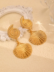 Macro view of golden shell earrings with spiral texture against a sandy textured background