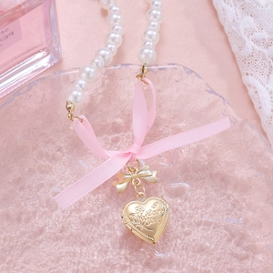 Detail of double-layer pearl necklace with pink ribbon bow and gold heart locket