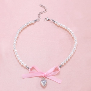 Pink ribbon bow pearl necklace with silver heart pendant on a soft pink textile