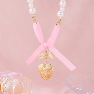 Detail showing pearl necklace with pink silk bow and engraved I Love You heart pendant