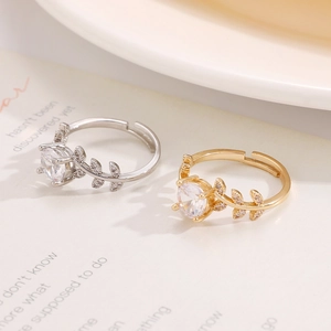 Detailed view of silver and gold laurel leaf moissanite rings on a vintage book