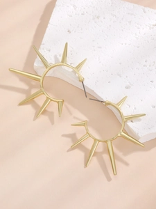 Detail von goldenen Creolen mit Sonnenstrahlen-Design und Zacken auf Steingrund