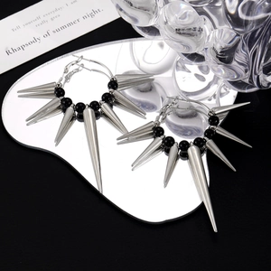 Macro shot of punk gothic hoop earrings with silver spikes and black beads on mirror
