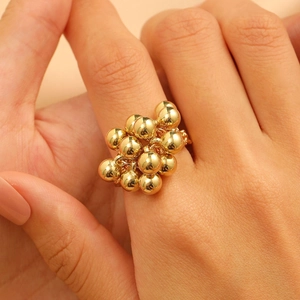 Close-up of golden cluster ring with polished beads on female index finger