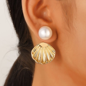 Close-up of a summer ocean-style earring featuring a white pearl and golden scallop charm