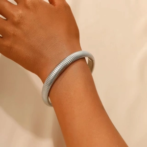 Close-up of a silver multi-layer stretch snake bone bracelet worn on a wrist
