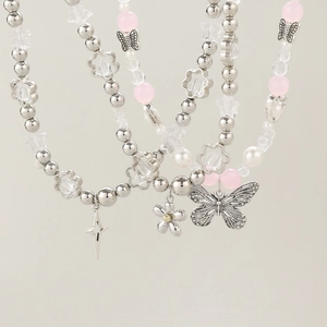 Dettaglio della collana di perle Y2K con farfalla d'argento e perline rosa lucide