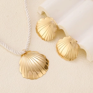 Detailed close-up of golden shell pendant necklace and earrings on textured background
