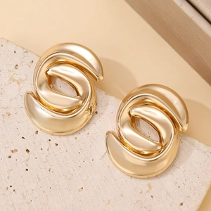 Macro detail of geometric interlocking gold-plated earrings on natural stone surface