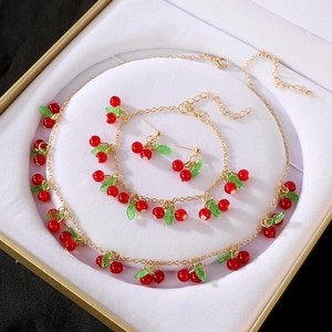 Detalle del juego de joyas de cereza roja con collar y pendientes en una caja de regalo