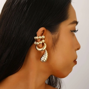 Detail of elegant gold layered ear cuff with a polished textured metal pendant on model