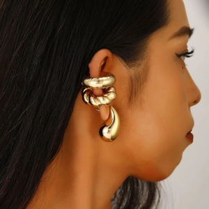 Close-up of golden drop earrings and spiral ear cuffs on a female model wearing jewelry