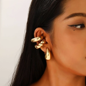 Close-up of gold-plated ear cuff set and teardrop earrings on a female model