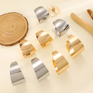 Poliertes Gold und Silber breite C-Creolen Set auf minimalistischem Holz-Dekor