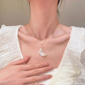 Detalle del collar con colgante de luna creciente y alambre dorado en una modelo