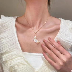 Modelo con collar de media luna dorada con nácar blanco y detalles de alambre enrollado a mano