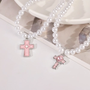 Detail of Gothic pearl necklace featuring pink cross and heart crystal charms in Y2K style