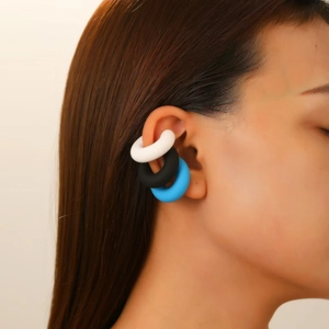 Close-up of matte silicone ear cuffs in black, blue and white on model ear