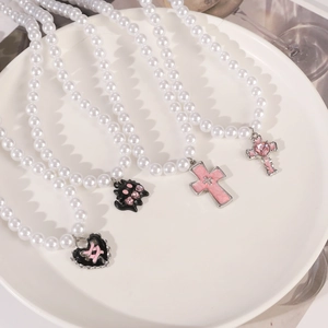Y2K Goth pearl necklaces with pink cross and cat pendants on a white porcelain plate