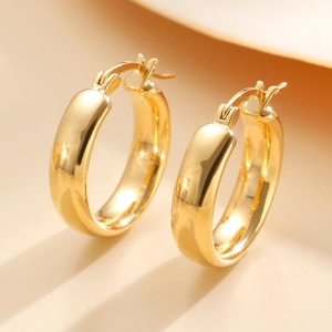 Macro close-up of polished gold-finished C-shaped hoop earrings with a secure clasp design