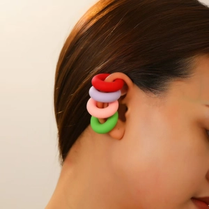 Detailed view of four colorful matte clip-on hoop earrings on a female model ear