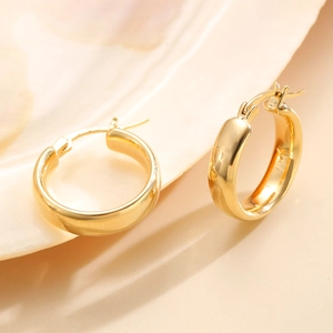 Detailed macro view of polished gold hoop earrings with secure lever-back closure design