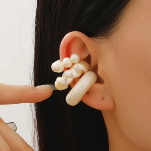 Close-up of minimalist white pearl ear cuffs with ribbed and twisted textures on ear