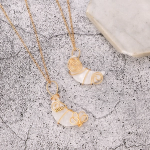 Collar artesanal con colgante de luna creciente envuelto en hilo dorado sobre piedra gris