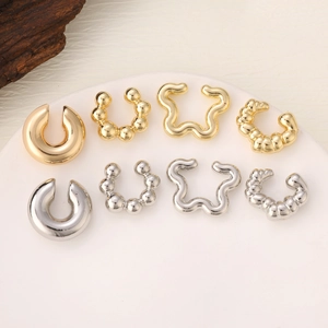 Detailed set of eight gold and silver hollow oval ear cuffs with polished metal texture