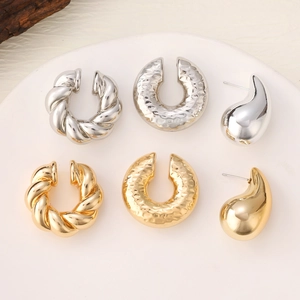Detailed close-up of textured gold and silver earrings on a white ceramic tray