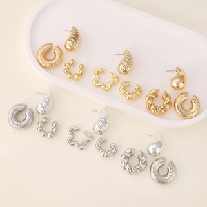 Macro view of assorted minimalist gold and silver hoop earrings on a white tray