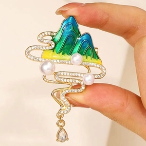 Detailed view of gold mountain brooch with enamel gradient, pearls, and teardrop zircon