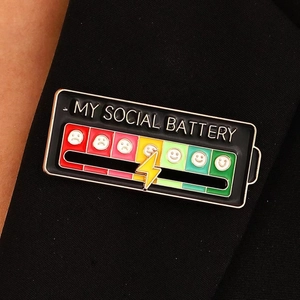 Detail of sliding social battery enamel pin with interactive lightning bolt on black fabric