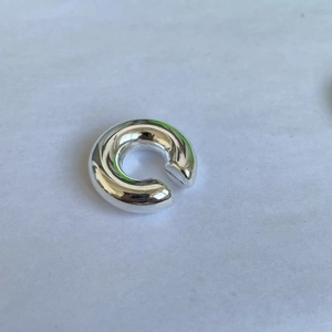 Detail of silver C-shaped chunky ear cuff with a high-polished metallic finish