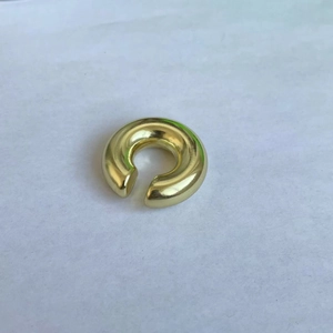 Macro shot of polished gold-plated hollow oval earring with a high-shine mirror finish