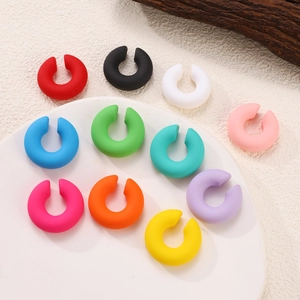 Flat lay of colorful C-shaped ear cuffs in 11 matte candy colors on a minimalist plate