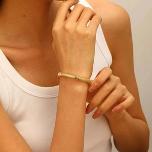 Close-up of a layered gold elastic bracelet with intricate spiral texture on a female wrist