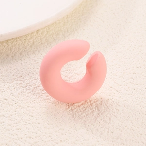 Macro shot of matte pink C-shaped acrylic earring detail on textured minimalist stone