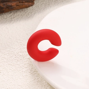 Macro shot of minimalist red C-shaped silicone ring showing matte texture and open design