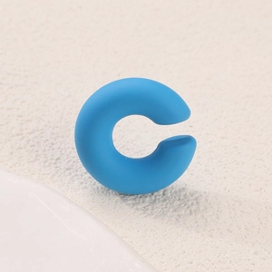 Macro shot of matte blue C-shaped clip earring with smooth frosted finish and modern look