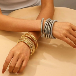 Close-up of chunky multilayer spring wire bangles in gold and silver metallic finish