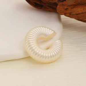 Detail of cream white spiral textured C-shape ear cuff with pearl-like luster finish