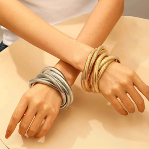 Detail view of gold and silver layered coil wrap bracelets on model's wrist