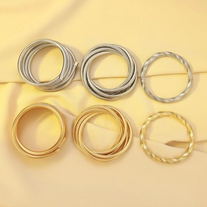 Detail view of gold and silver layered coil bracelets on elegant yellow satin fabric