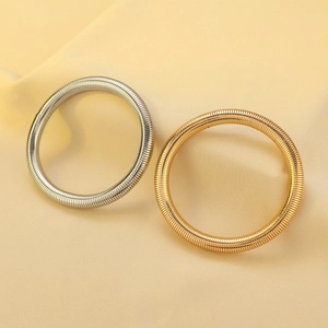 Detailed macro view of minimalist gold and silver coiled spring bangles on silk