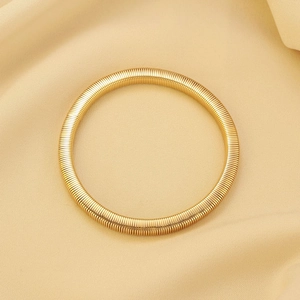 Macro view of golden multi-layer coiled Tubogas stretch bracelet with ribbed metallic texture
