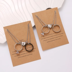 Detail of couple magnetic necklaces and ring set on premium brown greeting card